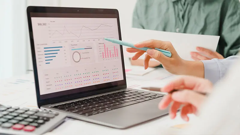 Pointing to a laptop computer with graphs.