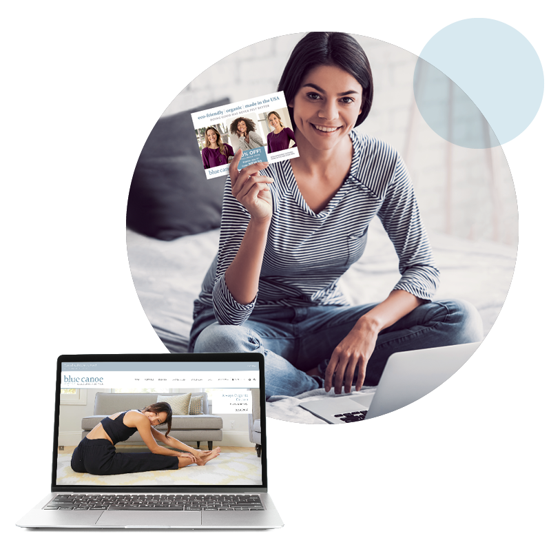 A woman holding up a direct mail postcard and a laptop showing a yoga company