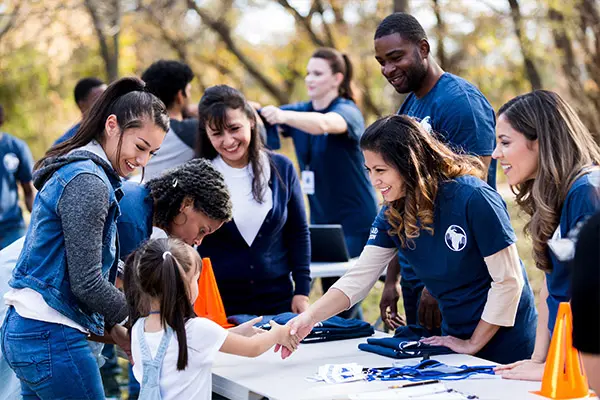 A group of non profit organization members handing out t-shirts and doing community outreach thanks to direct mail marketing