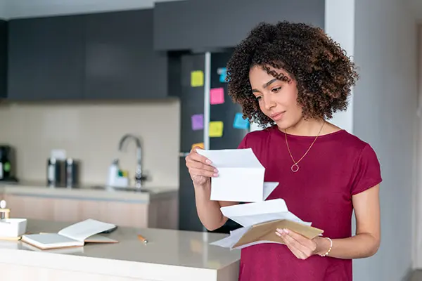 Woman in a red shirt reading mail at home in a kitchen