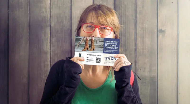 a woman holding up a direct mail automation card she received from a shoe company