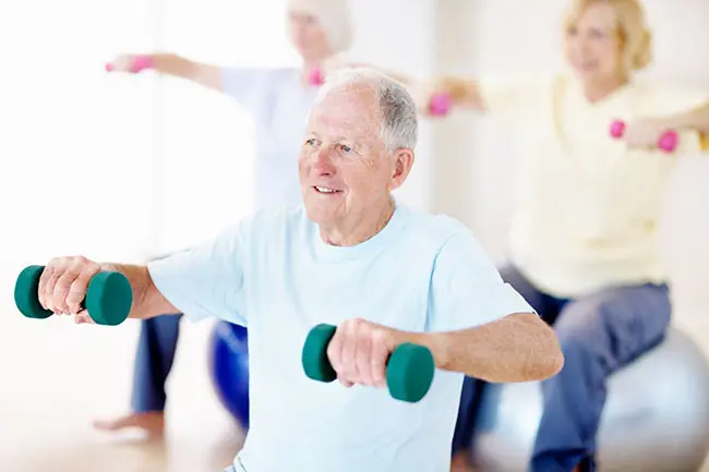 Retired man exercising with barbells in the gym